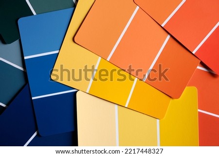 Generic color swatches scattered on a table. Swatches are in various autumnal shades of yellows and oranges, with complimentary blues as well. Fall color schemes. Interior design color pallet.