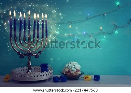 Image of jewish holiday Hanukkah background of menorah (traditional candelabra), doughnut and candles. Spinning tops with letters that mean, a great miracle happened here