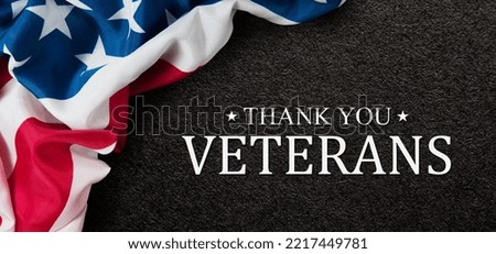 Closeup of American flag with Text Thank You Veterans on black textured background.