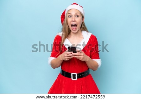 Young blonde woman dressed as mama claus isolated on blue background surprised and sending a message