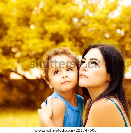 Photo of beautiful woman with little son on backyard in autumn, portrait of mother hugging adorable baby boy, young family playing games in autumn park, happy childhood, love concept