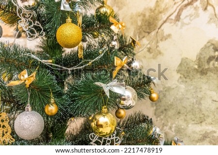 Christmas composition, gold and silver baubles, bows, animals, bells, lit garlands on a festive xmas fir tree against the decorative brick wall background. Copy-space. Winter holidays concept