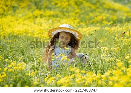 A girl is in a meadow with yellow flowers and poppies. It's spring and sunny outside. Happy childhood. Weekend in nature. Paint. Nature.