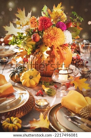 Thanksgiving celebration traditional dinner table setting concept. Festive decorated Thanksgiving table with centerpiece from big pumpkin and bouquet of flowers and candles