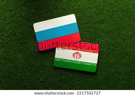 The flag of Russia and Iran on a green lawn background. Political negotiations, agreements. War. Sanctions. Armament.