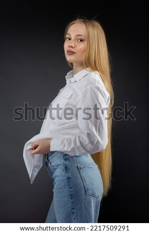 Blonde girl in jeans and white shirt over black gradient background