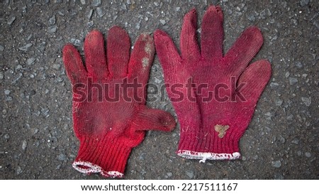 Dirty and torn cloth gloves on the cement floor with the hello gesture symbol
