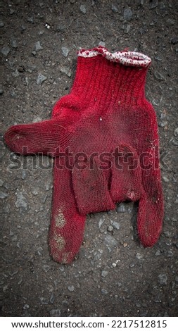 Dirty and torn cloth gloves on the cement floor and The sign of the horns is a hand gesture 