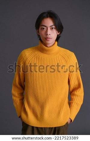 fashion model. Young man with hairstyle in yellow sweater on black background