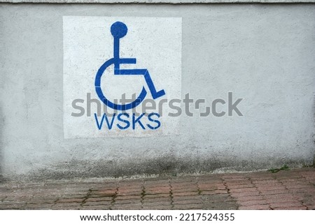 A disabled parking sign is painted on the wall of the building. disabled parking, disabled parking permit.