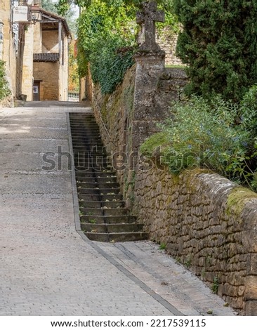 pathway with steps leading up between old stone walls and buildings in Sarlat-la-Caneda, a beautifully preserved 14th century medieval town in Dordogne, France