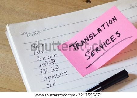 Language translation concept. Hello in different languages written on notebook with translation services memo on sticky note on desk. Selective focus.
