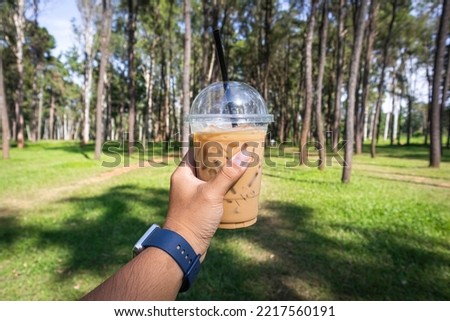close-up of hand holding a coffee cup in the middle of the forest