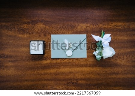Wedding details and accessories close-up: boutonniere, rings in a box, an envelope with a seal.