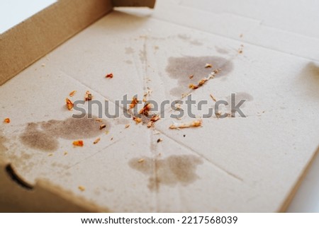 Eaten pizza, greasy traces and food crumbs on a cardboard box. Royalty-Free Stock Photo #2217568039
