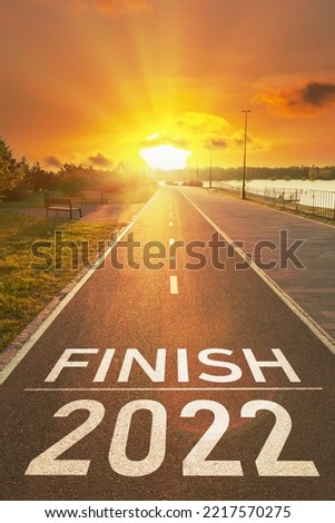 2022 year end concept. Motivational inscription for to sum up the year. Number of the 2022 year and finish is written on the asphalt on the empty sports path in the golden rays of the sun. Royalty-Free Stock Photo #2217570275
