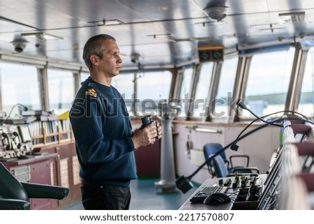 Deck officer with binoculars on navigational bridge. Seaman on board of vessel. Commercial shipping. Cargo ship. Royalty-Free Stock Photo #2217570807