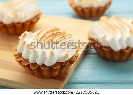 Appetizing lemon cupcakes with white cream on wooden board on blue background. Holiday, surprise, birthday, Valentine's Day. Top view.