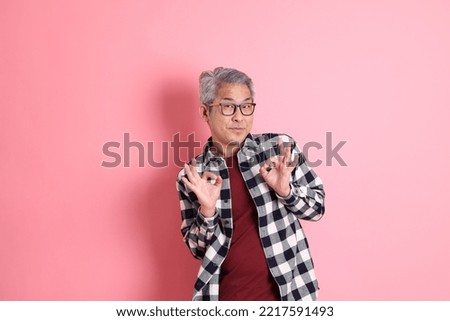 The 40s adult Asian man stnading on the pink background with casual clothes.