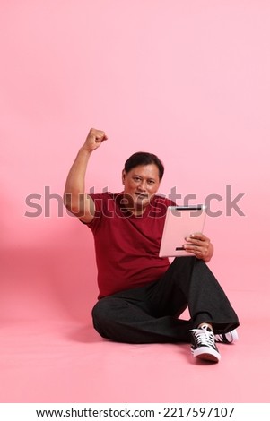 The 40s adult overweight Asian mansitting on the pink background.