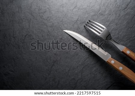 Black stone slate board with fork and knife, top view with copy space.