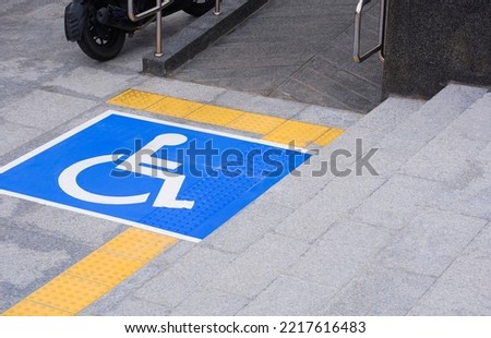 Accessible wheelchair Sign with Ramp and yellow Tactile paving line on different level marble Pavement surface with stairs in public area
