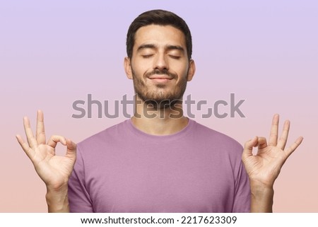 Happy smiling man standing with closed eyes, having relaxation while meditating, trying to find balance and harmony isolated. Yoga and meditation.