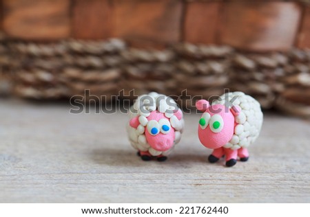Plasticine world - little homemade white sheep with blue and green eyes stand on a wooden floor, selective focus and place for text