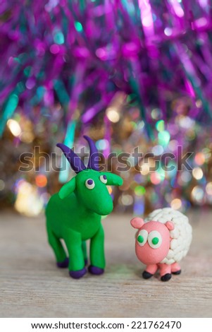 Plasticine world - little homemade green goat with purple horns and hooves and sheep stands on a wooden floor, selective focus and place for text