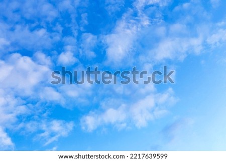 White curly clouds on the blue sky. Textured background for design. Selective focus