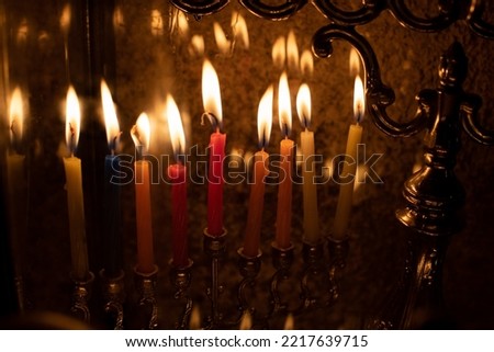 Multi-colored, wax Hanukkah candles burn in a menorah during celebration of the Jewish festival of lights. 
