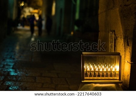 Glass vials hold oil and burning wicks in a menorah glowing brightly on a Jerusalem street on the eighth night of the Jewish festival of Hanukkah. 