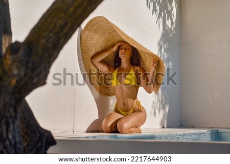 Attractive woman hiding from hot sun under big straw hat Royalty-Free Stock Photo #2217644903