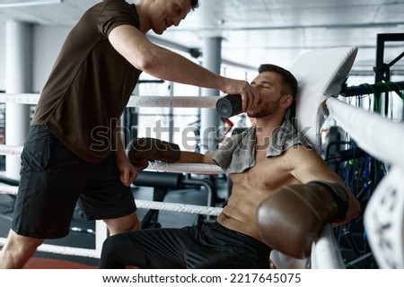 Trainer refreshing young boxer in ring corner