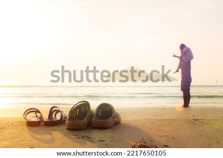 Father and daughter take off their sandals and lay on the beach. Daughter rides father's neck for a morning walk.