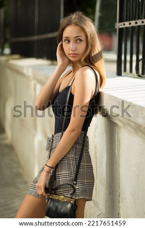 Gorgeous young brunette model posing outdoors in summer fashion outfit.