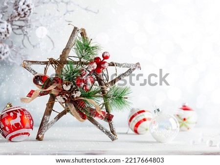 Christmas still life with decorated wooden Christmas Star, pine cone and baubles on light background. Winter festive concept.