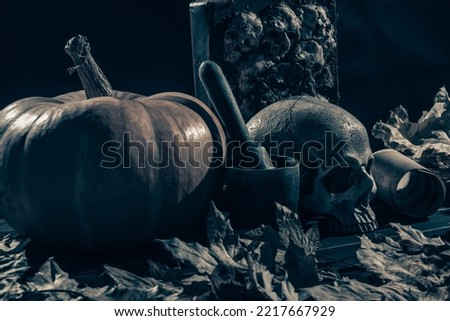 Pumpkin, skull and autumn leaves on a table.