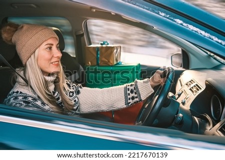 Woman Giving Gifts. Female is holding presents and delivering them on her car to Home. Holidays concept. Driving car in Christmas Eve. People In A Snow-Covered Forest. Sunny Cold Winter Day.