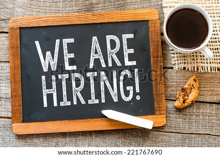 We are Hiring ! handwritten with white chalk on a blackboard, cup of coffee and biscuit on a wooden background  Royalty-Free Stock Photo #221767690