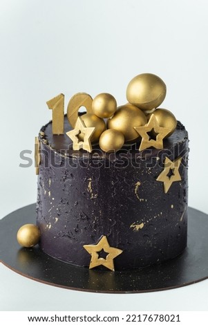 Luxury cake with dark blue cream cheese frosting decorated with golden chocolate stars and spheres. Birthday space themed cake on the white background