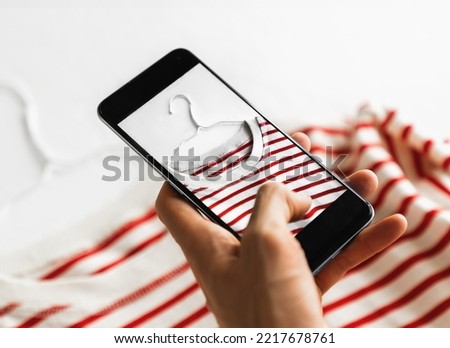 Man taking photo of striped t-shirt on smartphone 