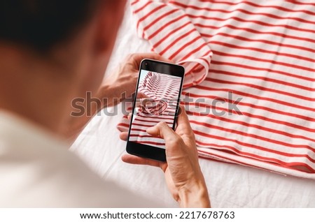 Man taking photo of striped t-shirt on smartphone 