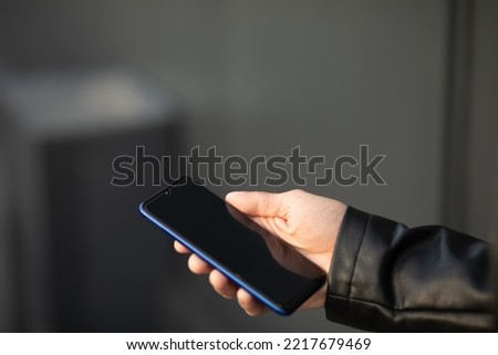 Closeup image of male hands with mobile phone, searching internet or social networks, blurred background