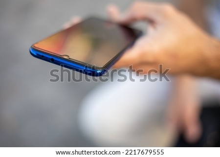 Closeup image of an unrecognizable young modern man holding mobile smartphone in hand,  chatting via internet application outdoor