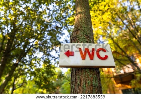 WC sign on a tree in the forest
