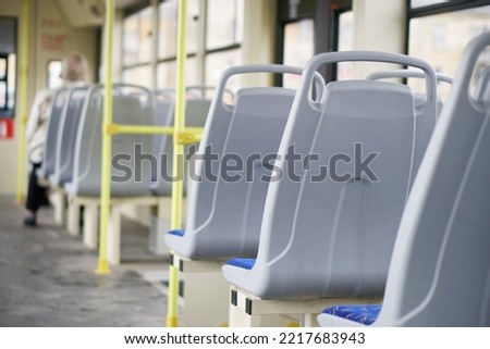 Plastic seat backs in an empty interior of a city tram, trolleybus or bus. Inside view. Selective focus. Small zone of sharpness. Daylight Royalty-Free Stock Photo #2217683943