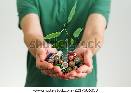 Leaf grows from a Alkaline batteries in hands. Green energy a symbol of clean energy resources. Concentration of waste recycling and environmental pollution Royalty-Free Stock Photo #2217686833