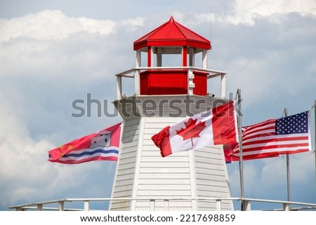 Canadian and American flags on a red and white lighthouse at Confederation Basin Marina in Kingston, Ontario
