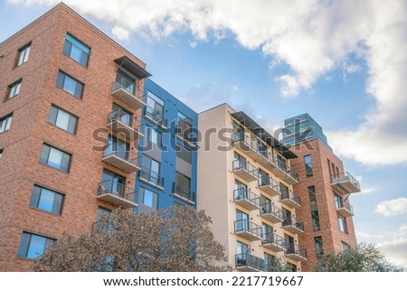Residential building with balconies and red brick wall against sky and clouds. Apartments and housing complex amidst scenic nature views in Austin Texas.